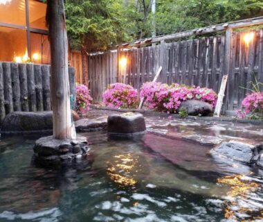 Outdoor stone onsen bath with azalea blooms at Hotel Uguisu in Iwate Tōhoku