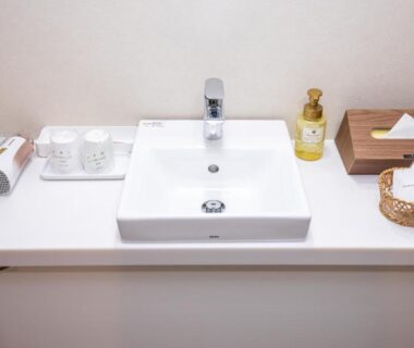 White vanity sink with faucet, soap, cups, tissue box and wicker tray in Hotel Umenoyu bathroom, Nagano