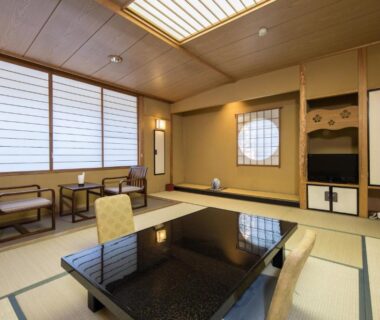 Traditional tatami room with low glossy table, shoji screens and seating area at Hotel Umenoyu in Nagano