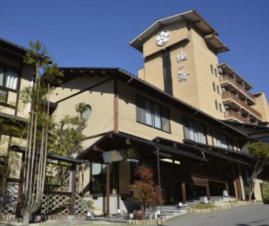 Traditional ryokan exterior at Hotel Umenoyu with entrance and clock tower in Nagano