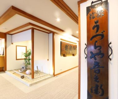 Entrance lobby with wooden name plaque, small rock garden, and shoji-style partitions at Hotel Uzuraya, Nagano