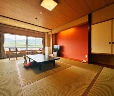 Traditional tatami room with low table, cushions, sliding doors and large window overlooking Nagano mountain landscape