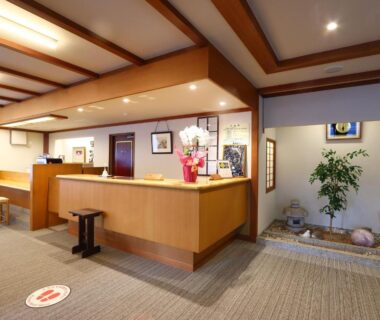 Wooden reception desk with seating and indoor rock planter at Hotel Uzuraya, Nagano