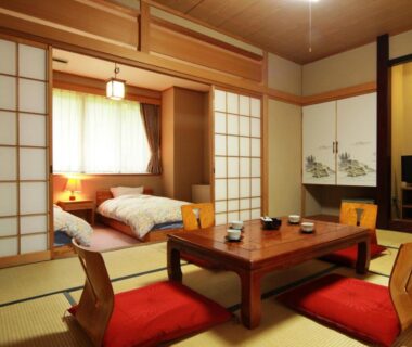 Tatami floor, low table with zabuton cushions, futon beds behind shoji at Hotel Wakatsuki in Nagano