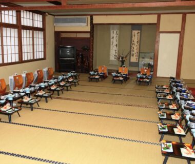 Traditional tatami room set with low dining tables and place settings for a communal meal at Hotel Wakatsuki, Nagano