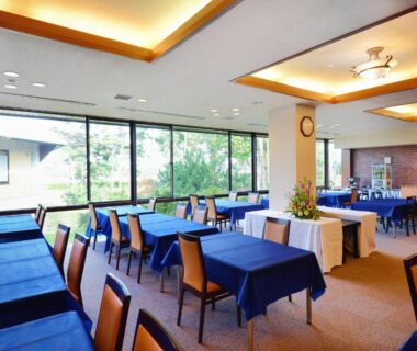 Dining area with blue tablecloths at Hotel Wellness Notoji in Ishikawa overlooking courtyard greenery