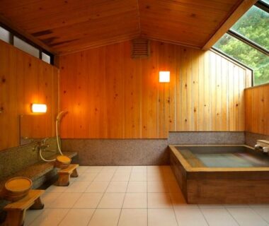 Indoor wooden bath with stools and hand showers at Hotel Yamadaya in Shizuoka, Chūbu, Japan
