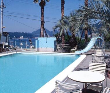 Poolside with slide, palm trees and lounge chairs at Hotel Yamadaya in Shizuoka
