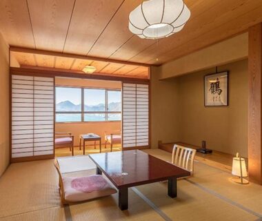 Traditional tatami room with low table, zabuton cushions, shoji screens and water view at Hotel Yamadaya, Shizuoka