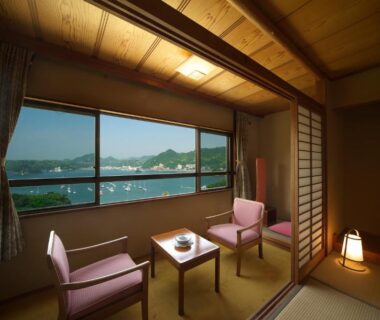 Tatami room with window seating overlooking water and hills at Hotel Yamadaya in Shizuoka, Chūbu, Japan