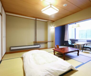 Traditional tatami room with futon, low table and window seating at Hotel Yudanaka, Nagano