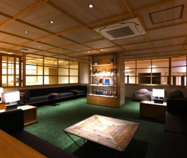 Spacious ryokan lounge with low wooden table, shoji screens, sofas and green carpet at Hotel Yudanaka in Nagano