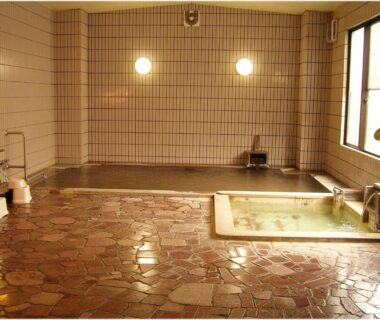 Tiled indoor onsen with soaking tub and washing area at Hotel Yume-no-yu, Nagano