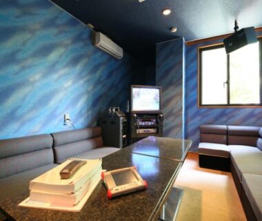 Karaoke room with blue walls, booth seating and TV at Hotel Yume-no-yu, Nagano, Chūbu