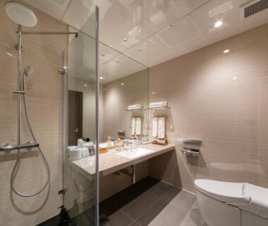 Glass shower stall, double vanity and toilet in bathroom at Hotel Yumeshizuku, Kumamoto