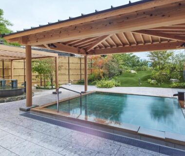 Wood-roofed onsen bath beside garden at Hotel Yumeshizuku in Kumamoto, Kyūshū