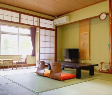 Traditional tatami room with low table, zabuton cushions, shoji screens and window seating at Hotel Yumoto, Niigata