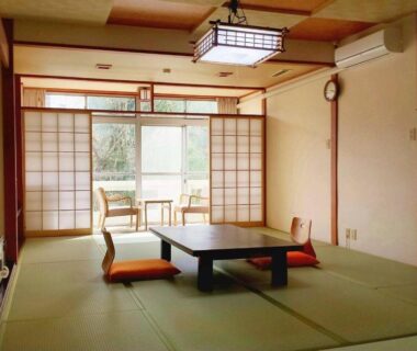 Traditional tatami room with low table, zabuton cushions and shoji screens at Hotel Yumoto in Niigata