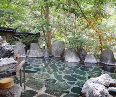Stone outdoor onsen pool with wooden stools at Hotel Yunishigawa, Tochigi, Kantō, Japan