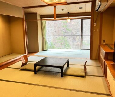 Tatami room with low table and cushions at Hotel Yunishigawa in Tochigi