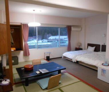 Tatami area with low table and twin beds at Hotel Yunojin in Gunma, Kantō, Japan