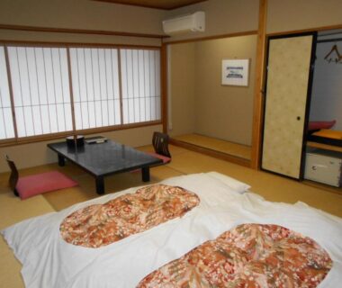 Tatami room with futon bedding, low table and shoji screens at Hotel Yunojin in Gunma Kanto