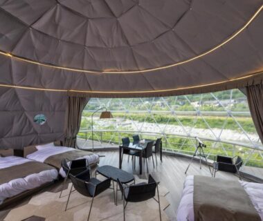Spacious dome tent with multiple beds, seating and panoramic window at Hotel&Glamp YAMABOSHI in Nagano, Chūbu