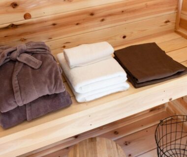 Folded robes, towels and toiletries on a wooden shelf inside Hotel&Glamp YAMABOSHI, Nagano