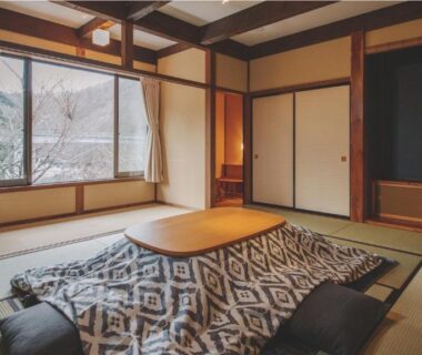 Traditional tatami room with kotatsu, zabuton cushions, shoji screens and wooden beams at Hotorinite in Yamanashi Chūbu