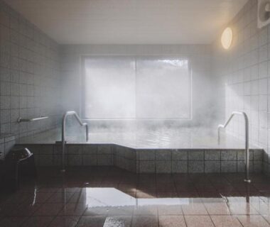 Steaming indoor tiled onsen bath with metal handrails and fogged window at Hotorinite, Yamanashi, Chūbu
