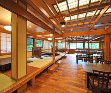 Traditional tatami dining area with low tables, wooden beams and garden-facing windows at Houshi Onsen Chojukan in Gunma