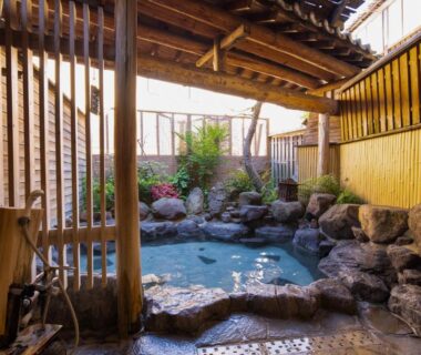 Rock-lined outdoor onsen bath with wooden fence at Hozanso Beppu, Ōita, Kyūshū, Japan