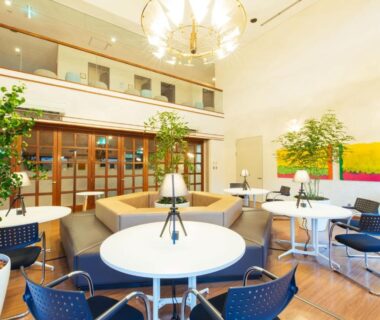 Bright lounge with round tables, chairs, chandelier and plants at IKOI Villa Nagano