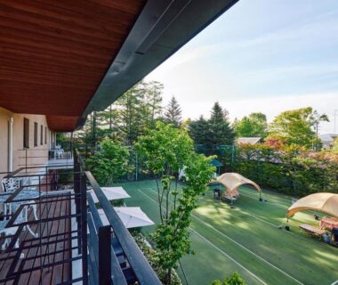 Balcony and chairs overlooking grassy lawn with dome tents at IKOI Villa in Nagano