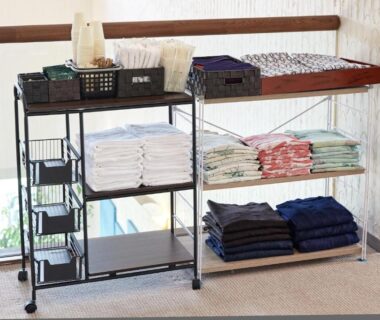 Metal shelving with neatly folded towels and linens near a window in ryokan interior, natural light