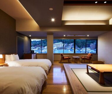 Spacious tatami room with low table, twin beds, large window at ITSUKUSHIMA IROHA in Hiroshima