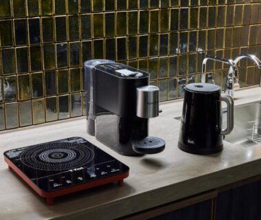 Compact kitchenette with induction hob, espresso machine, electric kettle and sink against tiled backsplash in ryokan room