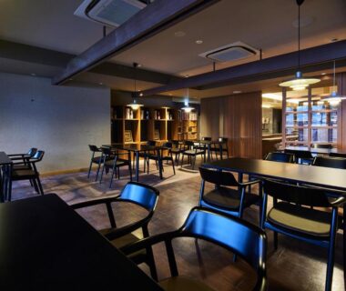 Spacious wooden dining area with tables, chairs and warm pendant lighting at ITSUKUSHIMA IROHA in Hiroshima