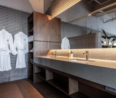 Changing area with hanging white robes, long sink and wooden shelving at IZU RETREAT, Shizuoka