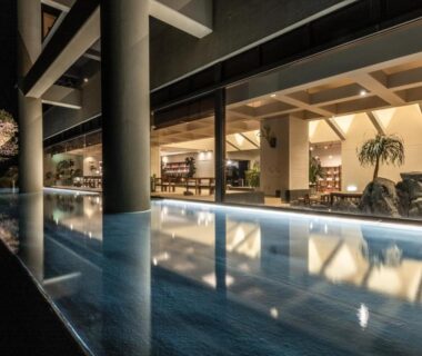 Lit indoor bathing pool with columns, wooden beams and seating area at IZU RETREAT in Shizuoka