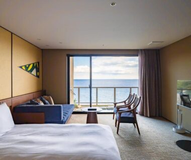 Bed and lounge area with balcony overlooking sea at IZU RETREAT by Onko Chishin in Shizuoka