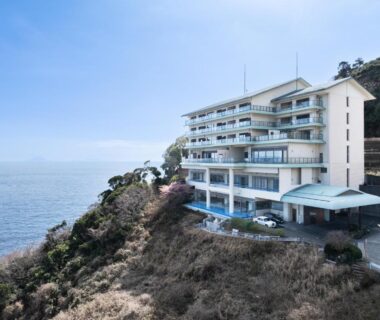 Multi-story ryokan perched on coastal cliff with balconies overlooking the sea in Izu, Shizuoka