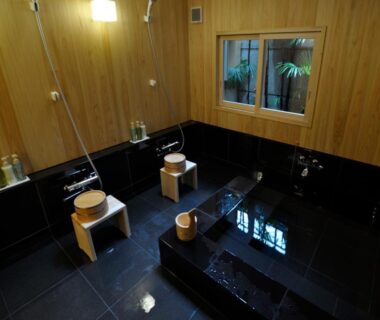 Indoor tiled bath with stools and wooden buckets at IZUYASU Traditional Kyoto Inn