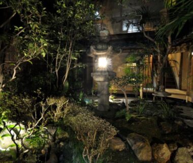 Nighttime courtyard garden with stone lantern and wooden verandas at IZUYASU ryokan in Kyoto, Kansai Japan