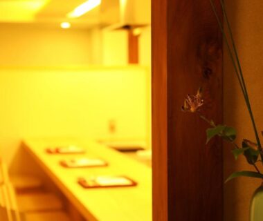 Warm lit wooden counter with place settings and vase at IZUYASU Traditional Kyoto Inn Kyoto, Kansai, Japan