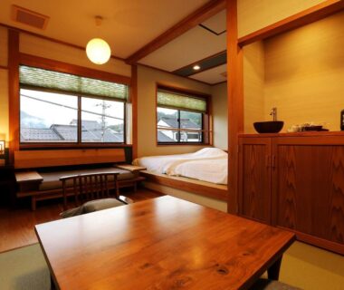 Tatami room with low wooden table, futon bedding and wood-framed windows at Ichidaya, Hyōgo, Kansai