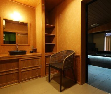 Wooden washbasin and chair with doorway to tiled bathing area at Ichidaya, Hyōgo