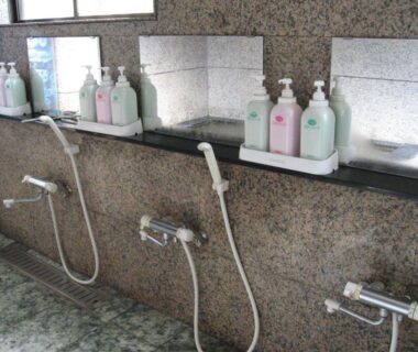 Tiled bathing stations with handheld showers and toiletry bottles at Ichifujiso ryokan in Yamanashi, Chūbu
