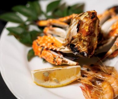 Grilled crab and prawns with lemon wedge on white plate at ryokan Ichifukuso in Saga