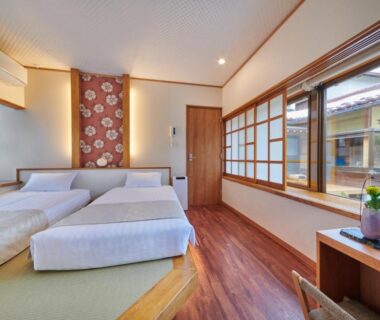 Bright ryokan room with raised tatami platform, twin beds, shoji screens and wooden flooring at Ichinomatsu in Gifu